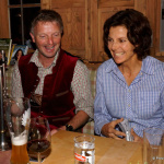 Lachende Gesprächsrunde in gemütlicher Atmosphäre, gesellige Stimmung mit Getränken und Instrument.