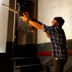 Ein Mann in einer checkered Bluse hält eine auf einen Plüschhasen gerichtete Waffe.