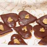 Schokoladene Herz-Kekse mit Walnüssen auf dekorativem Teller.