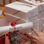 Detailaufnahme von Keksschachteln und einem Hinweis auf "Rumkugeln" in gemütlicher Umgebung.