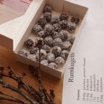 Rumkugeln in einer Box auf einem Holzuntergrund, daneben ein Rezept mit Zutatenliste.