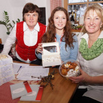 Drei Damen präsentieren köstliche Kekse in einer gemütlichen Umgebung mit festlicher Dekoration.