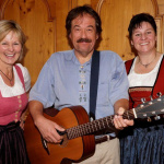 Peter Blaikner mit Bäuerinnen im Trachtenkleid bei fröhlichem Auftritt im Gasthof Schörhof.