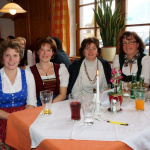 Sechs Bäuerinnen sitzen lächelnd am Tisch im Gasthof Schörhof bei einem unterhaltsamen Event.