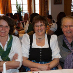 Drei Bäuerinnen in traditioneller Tracht lachen während eines Festes im Gasthof Schörhof.