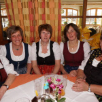 Fünf Bäuerinnen in Tracht lachen an einem Tisch im Gasthof während der Veranstaltung.