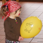 Kind im Piratenkostüm mit roten Tuch und gelbem Ballon beim Kinderfasching in Saalfelden.