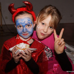 Kinder in fantasievollen Faschingskostümen mit buntem Gesichtsschmink und Süßigkeiten.