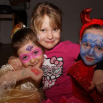 Drei fröhliche Kinder in bunten Kostümen beim Kinderfasching im Pfarrsaal Saalfelden.