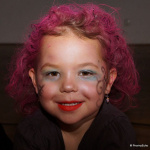 Fantasievoll verkleidetes Kind mit pinken Haaren und buntem Gesicht am Kinderfasching.