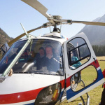 Hubschrauberlandeplatz in der Natur, Passagiere steigen ins Cockpit ein.