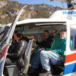 Gruppe von Männern sitzt in einem Hubschrauber mit Blick auf die Berge.