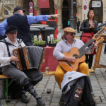 Marktmusik mit Akkordeon und Gitarre, Akteure in traditioneller Kleidung auf dem Wochenmarkt.