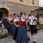 Traditionelle Trachtenfiguren tanzen vor dem Gemeindeamt in Lend, umgeben von Zuschauern.