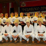 Traditionelle Trachtentruppe mit Kopfbedeckungen bei Volkstanzveranstaltung in Österreich.