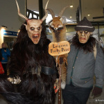 Zwei traditionelle Figuren mit Masken und Fellen stehen in einer Bergbahnstation.