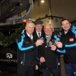 Vier Männer in Jacken präsentieren stolz Tickets vor der neuen Steinbergbahn in Leogang.